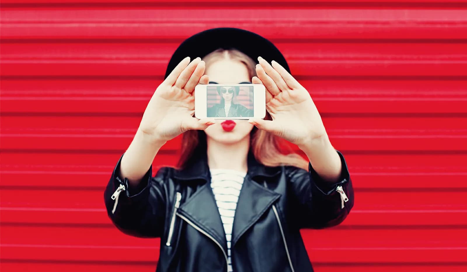 A female influencer holding her phone taking an selfie for social media.