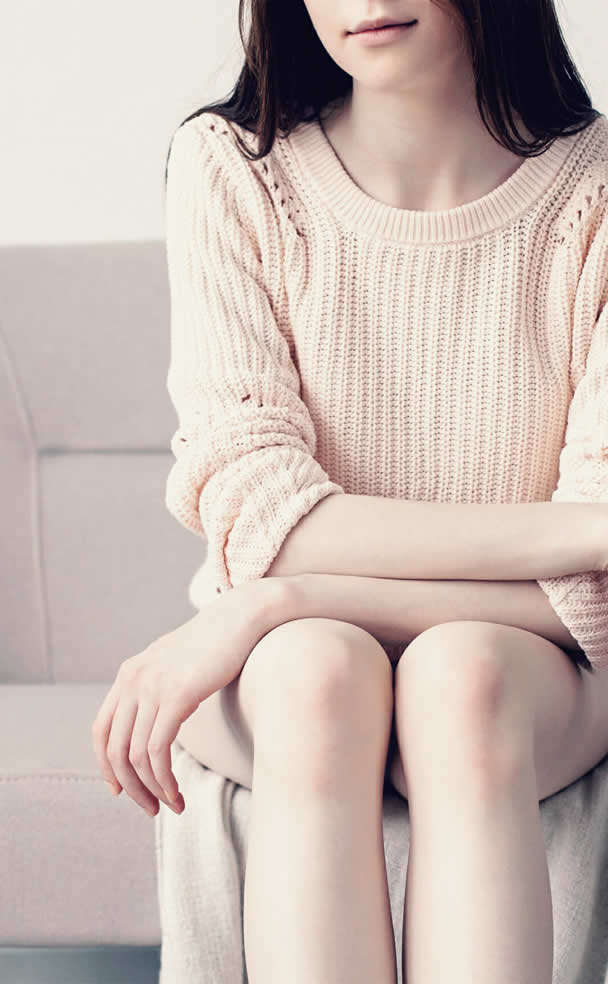 Woman in a Lily AI attributed sweater sitting on a couch in her home.