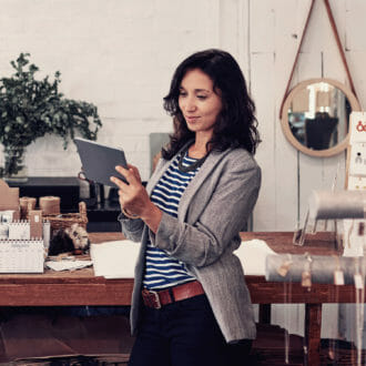 Woman on a tablet in her home shopping while surrounded by trendy home decor.
