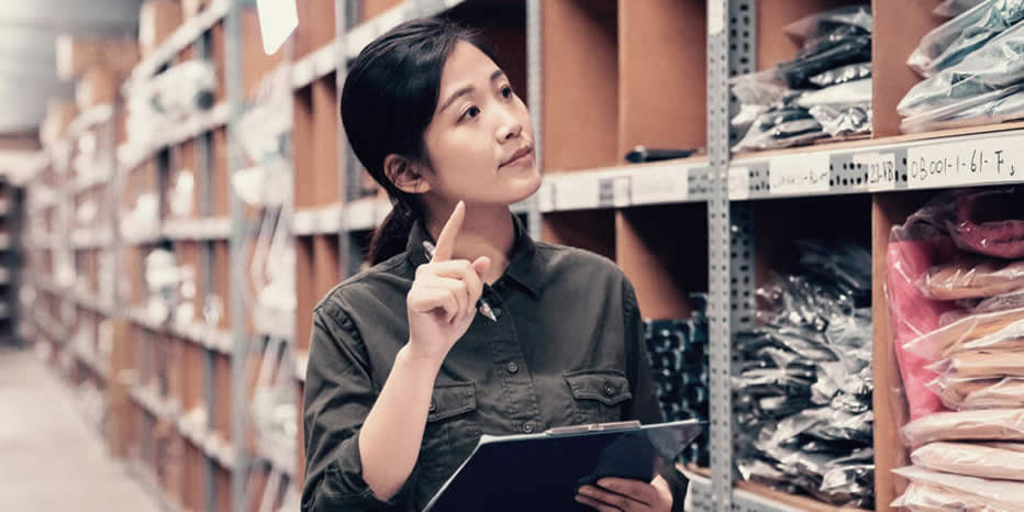 Woman taking stock of clothing in warehouse showcasing the benefit of Lily AI when doing item set-up.