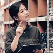 Woman taking stock of clothing in warehouse showcasing the benefit of Lily AI when doing item set-up.