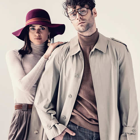 Male and female fashion models posing in fall attire complete with neutral coats and a floppy hat.