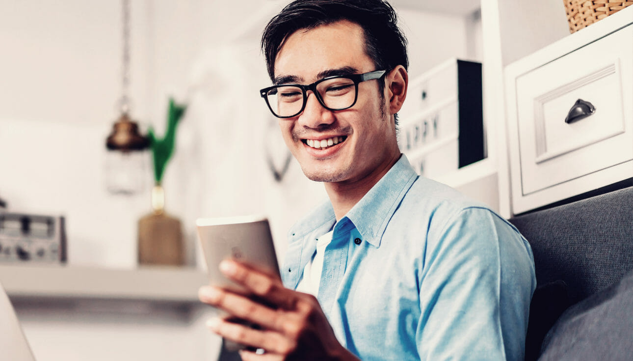 Man smiling at his phone while discovering new products while online shopping.