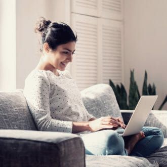 Woman smiling at her laptop while she is online shopping from the comfort of her home.