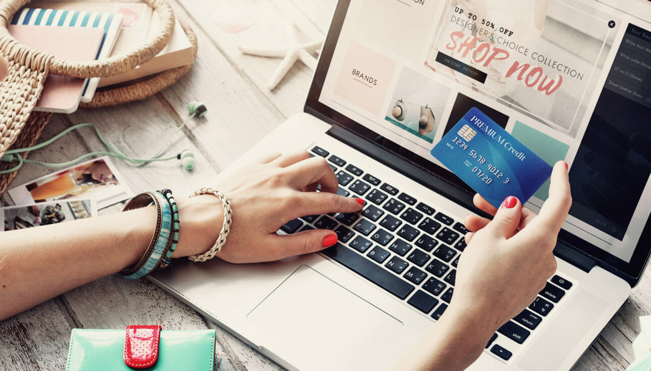 Woman holding a credit card while online shopping for fashion products.