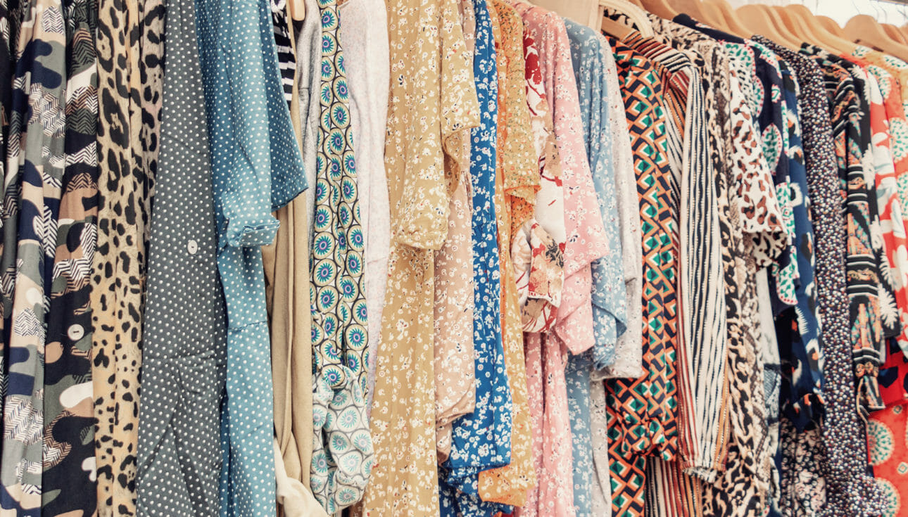 Image showing a variety of different clothing hanging on racks at a thrifting retailer.