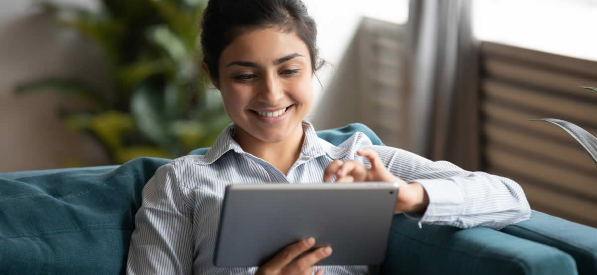 Happy young woman watching a video on her tablet about to request a demo from Lily AI.