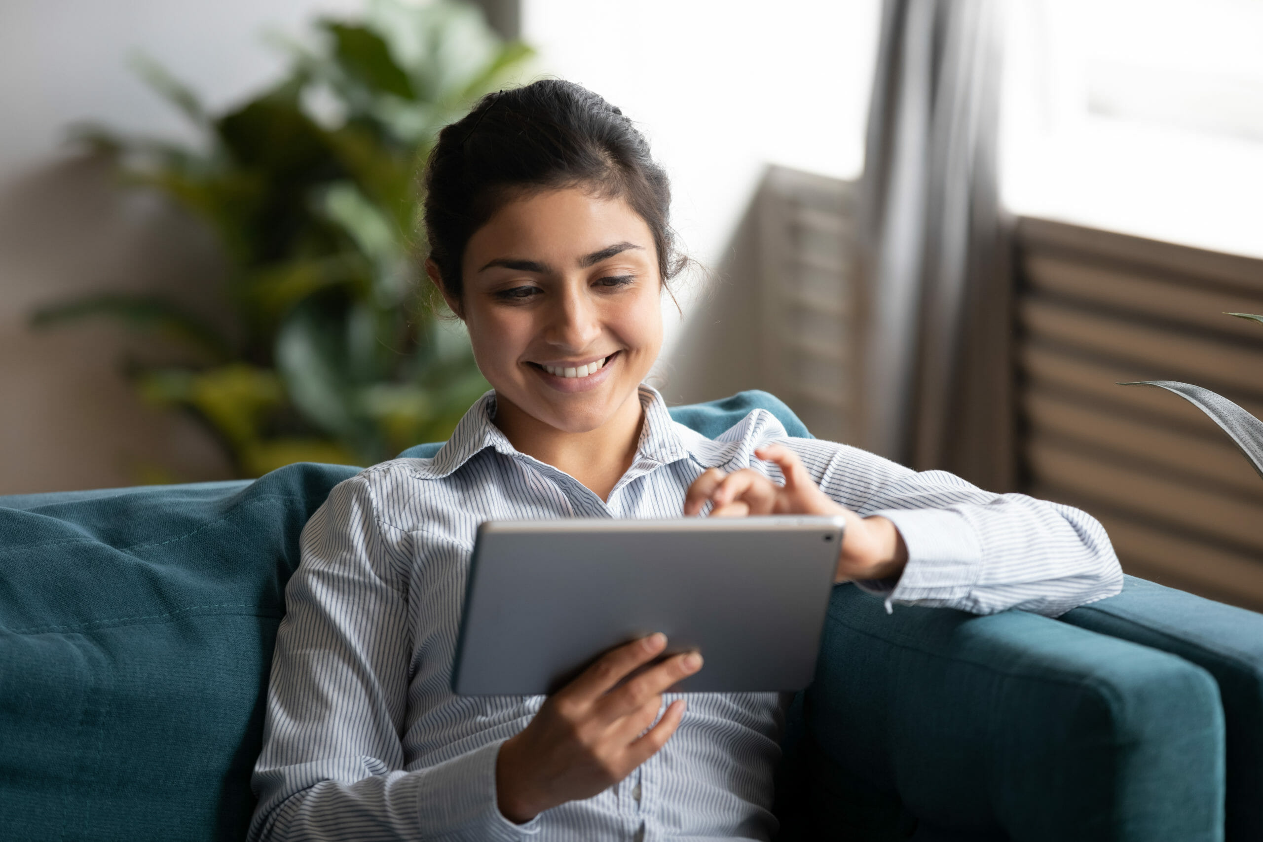 Happy young woman watching a video on her tablet about to request a demo from Lily AI.