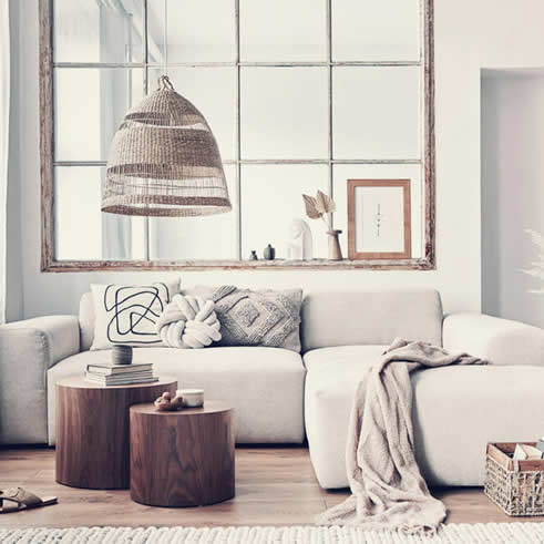Neutral soft home image of a living room with a sectional sofa and wooden accents.